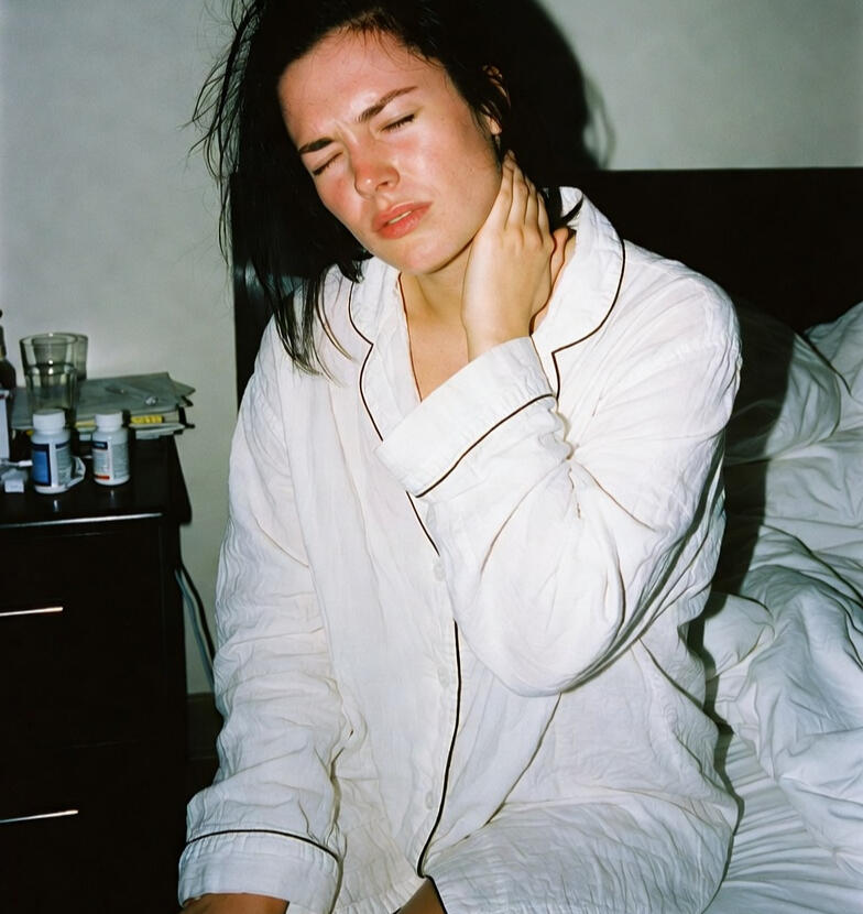 Person rubbing neck at desk or on edge of bed