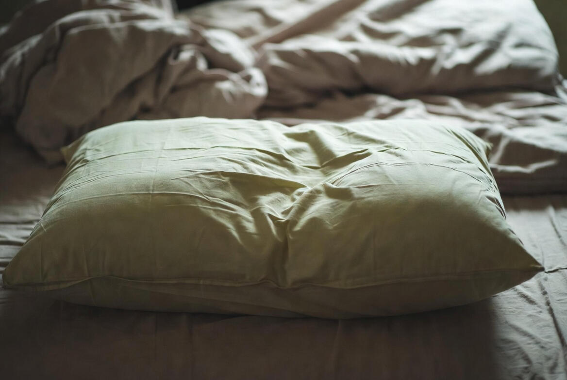 Person rubbing neck at desk or on edge of bed